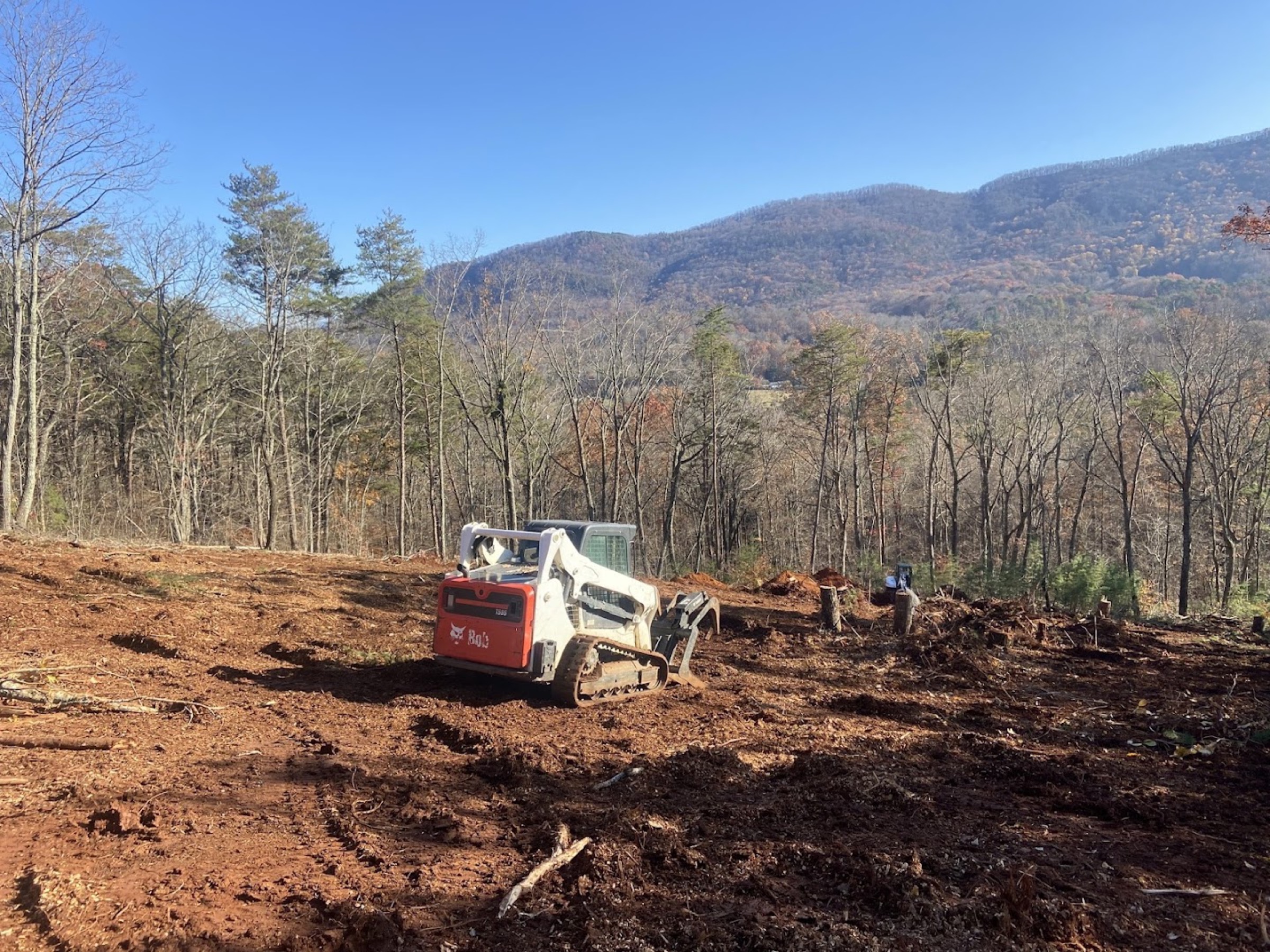 A cleared lot with the East Tennessee ridgeline behind after an Elite Tree Service job